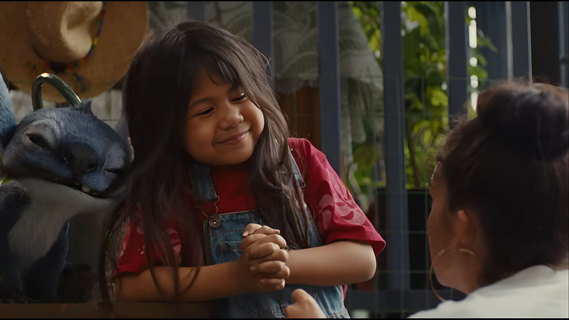 Lilo shares a moment with Nani as Stitch watches in Disney’s live-action Lilo & Stitch. (Image via Disney)
